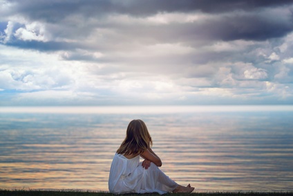 Woman looks at colorful light reflections over the lake waters